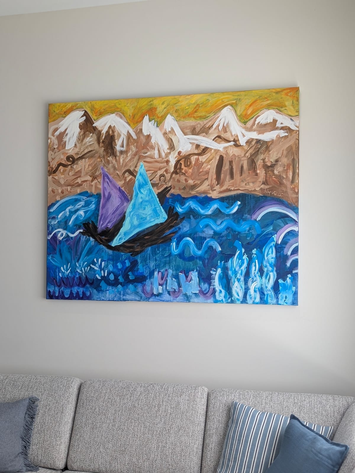 Custom painting of snow-capped mountains and a sailboat on blue water, commissioned for a living room