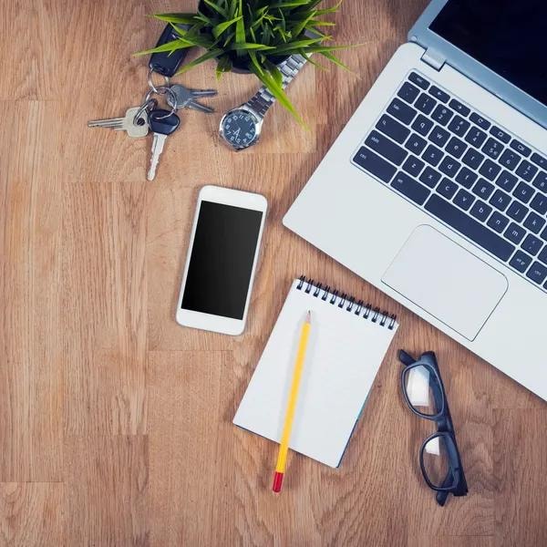 Laptop, notebook, and workspace essentials on a wooden desk